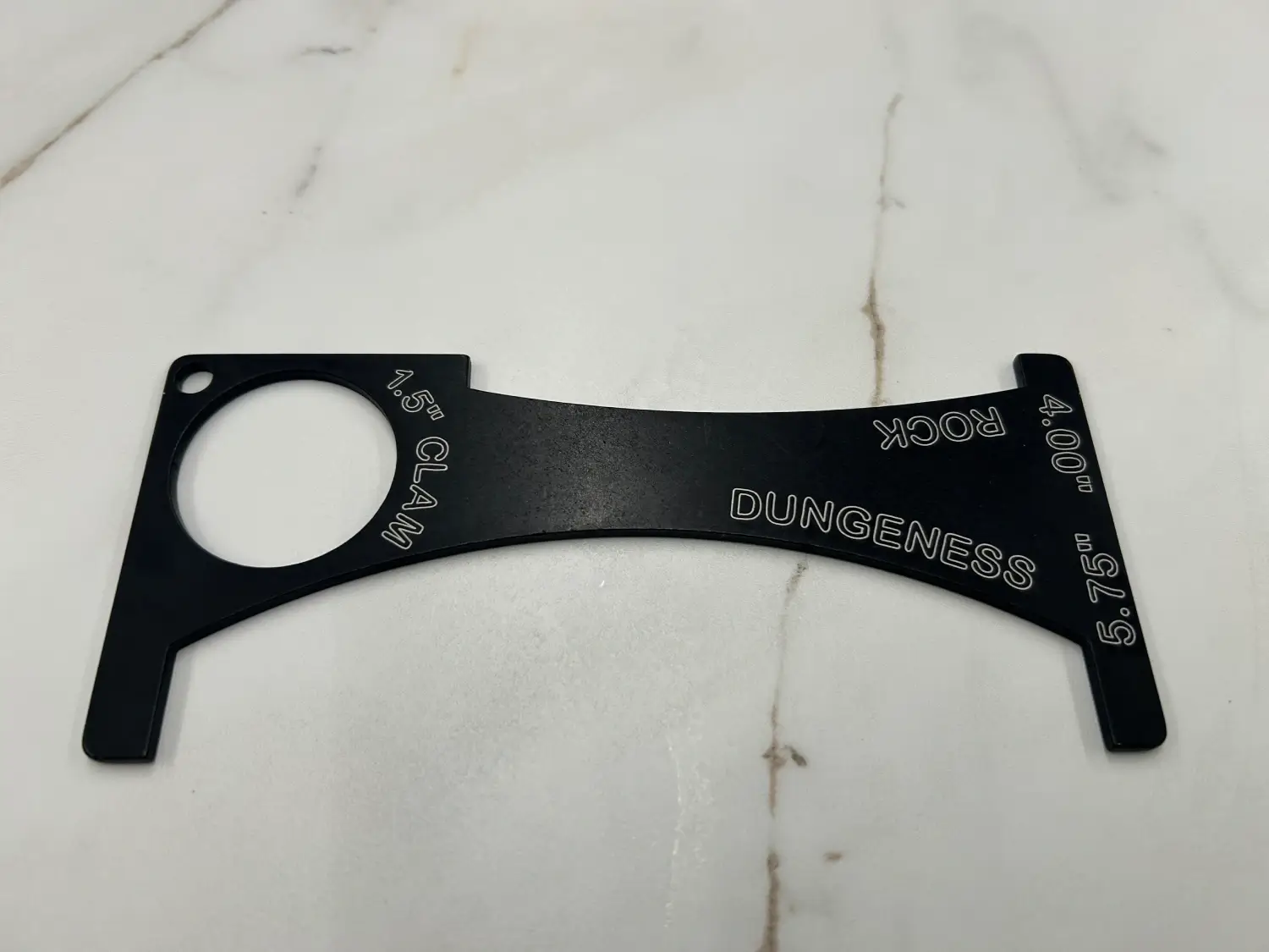 A black metal component labeled 'DANGER' and 'HOOK' on a white surface.